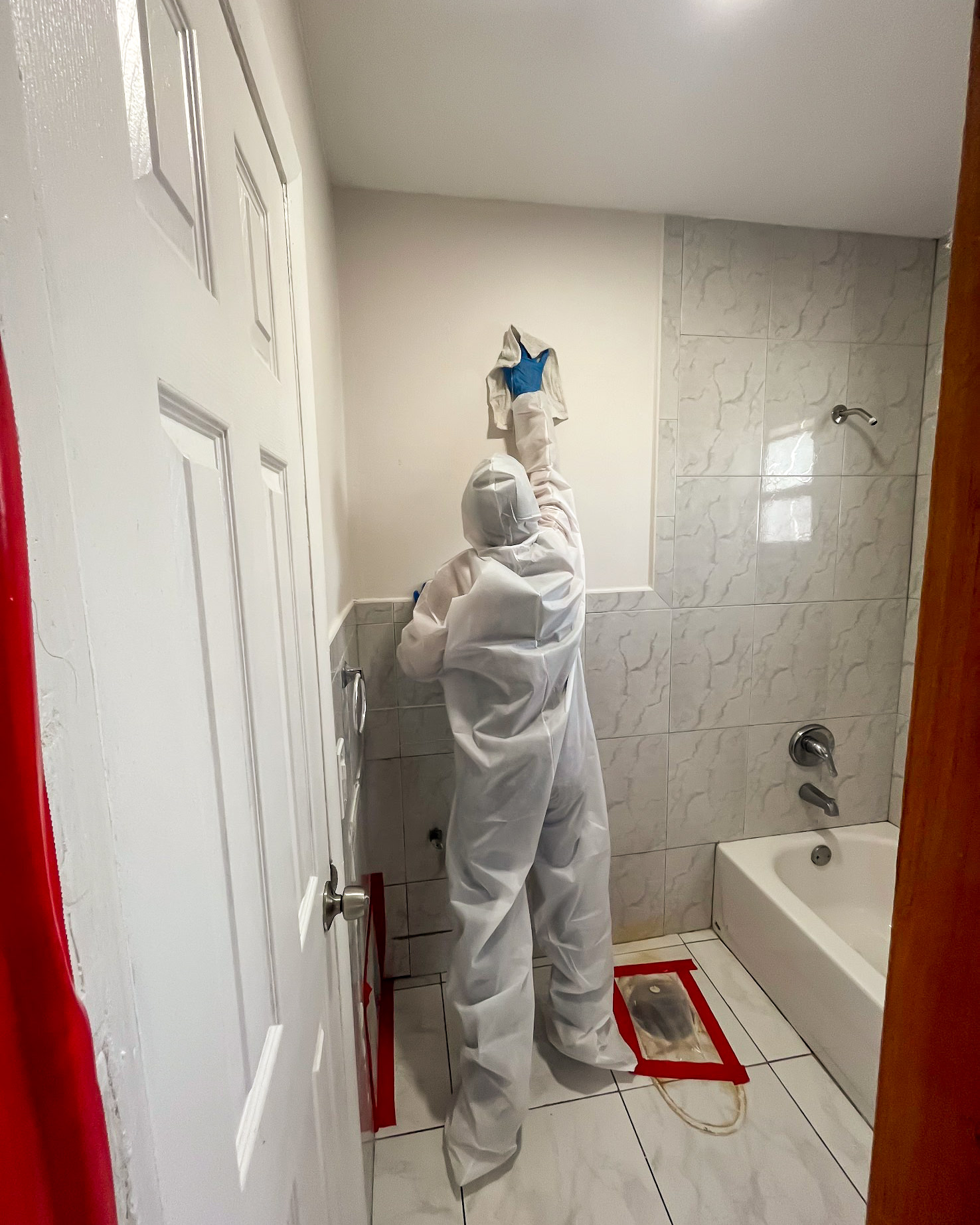 PPE-suited technician treating bathroom tiles for odor elimination