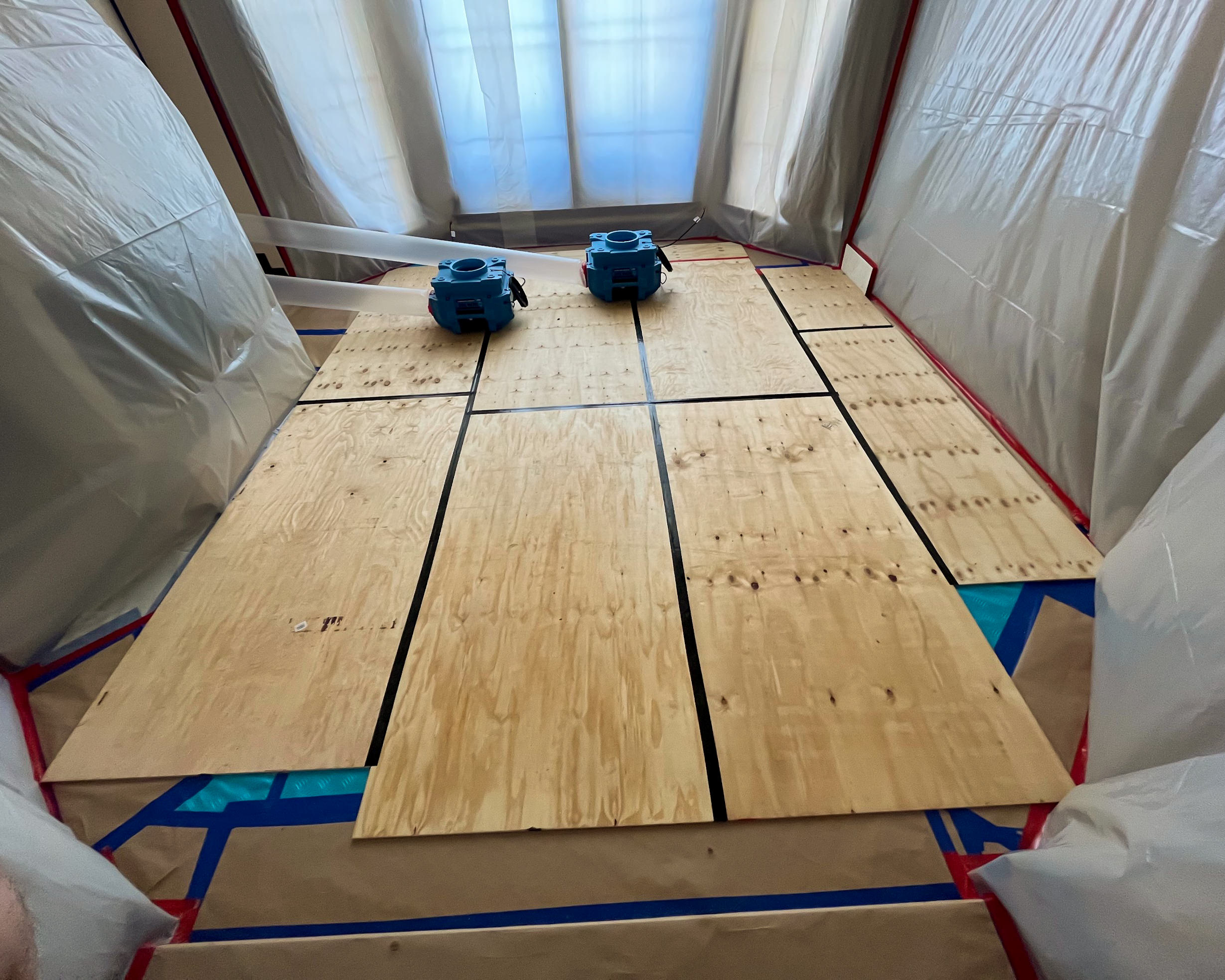 Air movers on plywood subfloor inside containment tent during catastrophe response