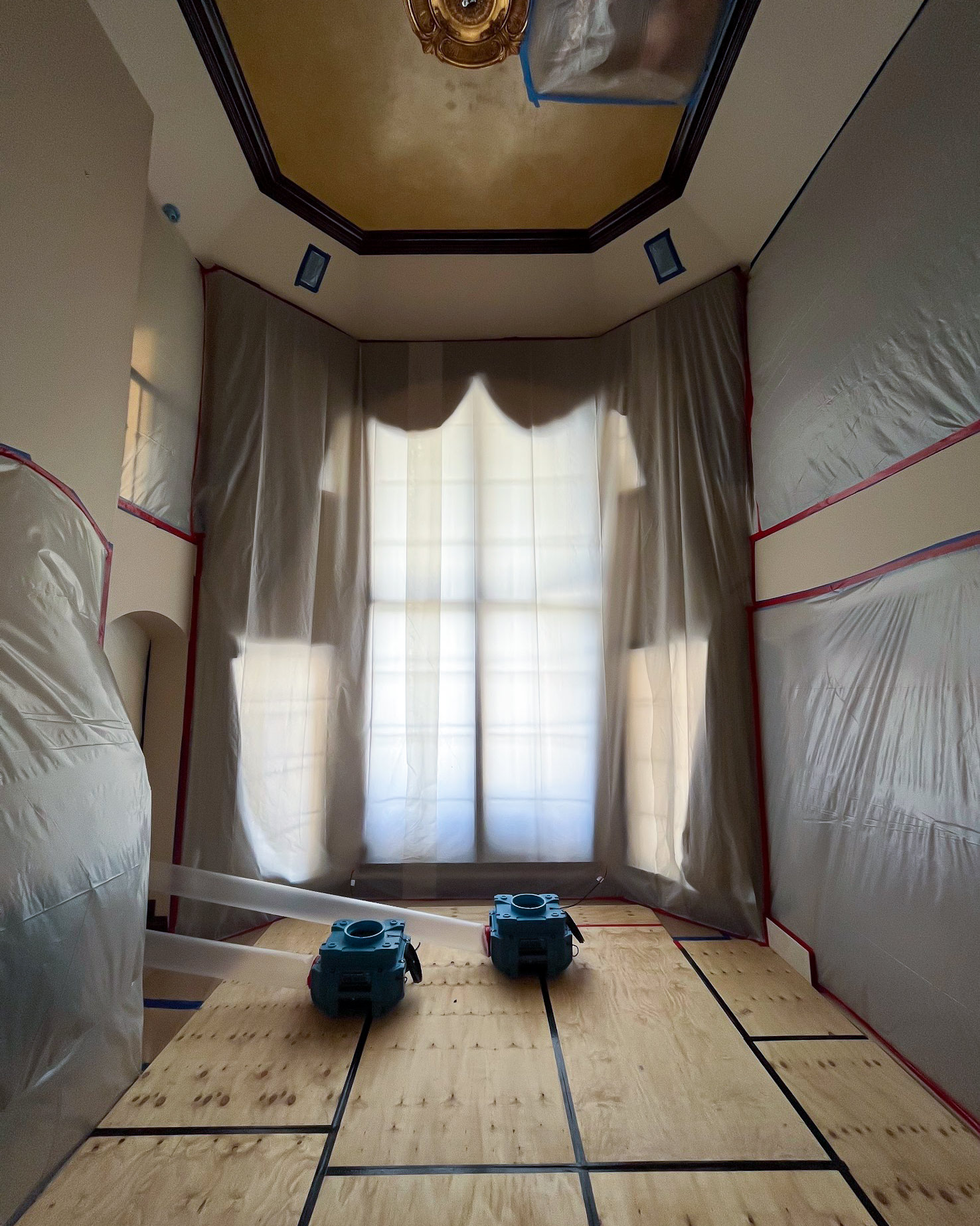 Room fully sealed with plastic sheeting — air movers running during drying phase