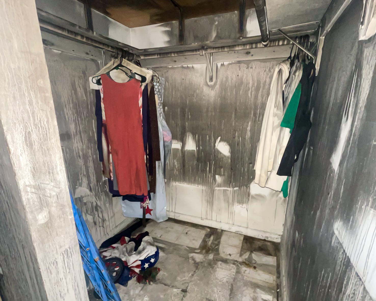 Smoke and soot-stained closet with hanging clothes — fire content damage before restoration