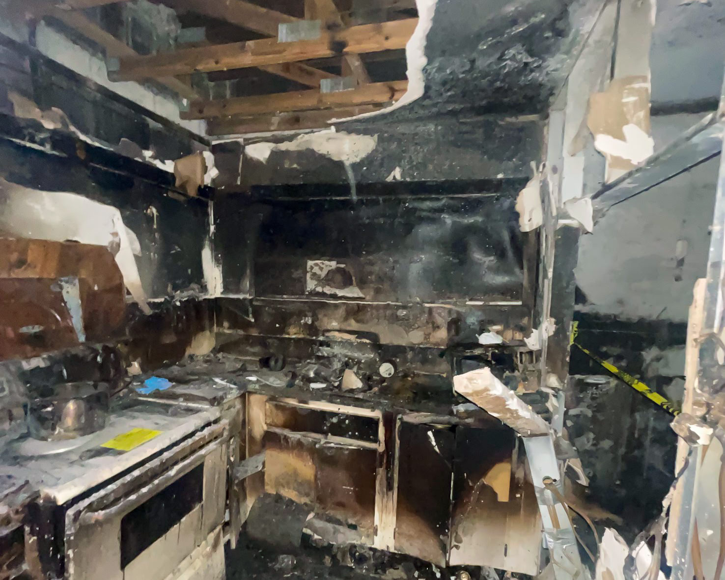 Fire-destroyed kitchen — complete soot damage, stove and cabinets burned