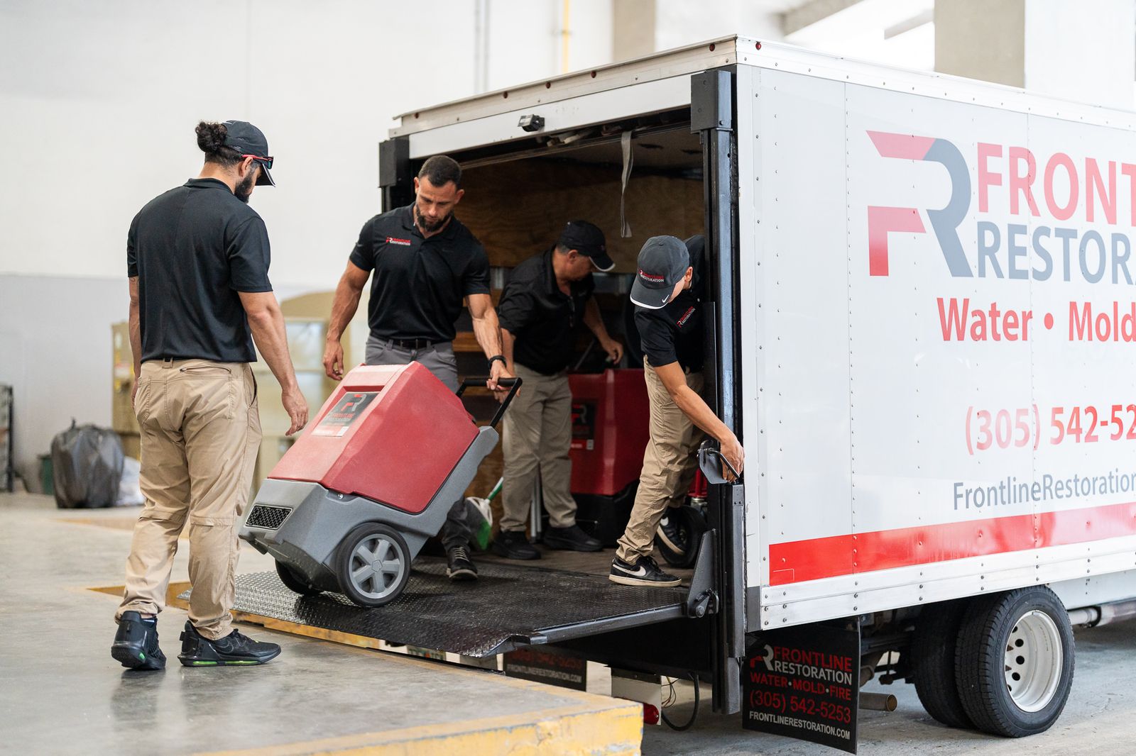 Crew unloading dehumidifiers from the Frontline Restoration box truck on arrival