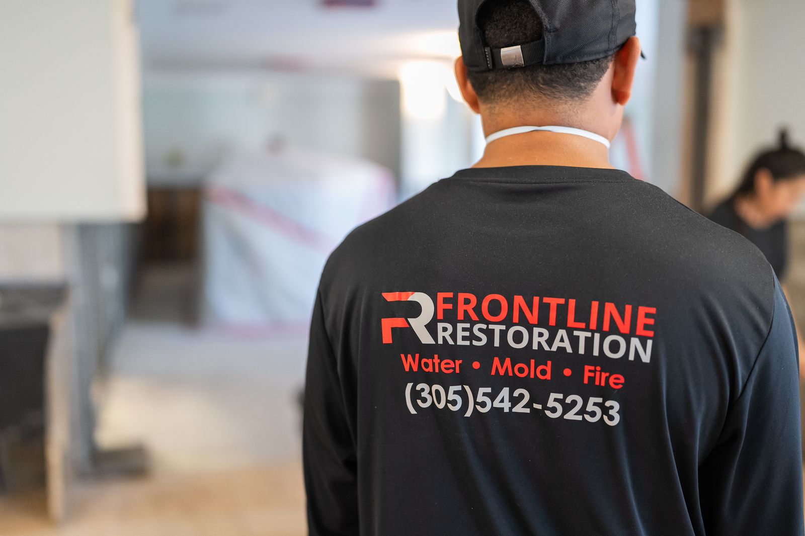 Technician in a branded Frontline Restoration shirt working inside a property