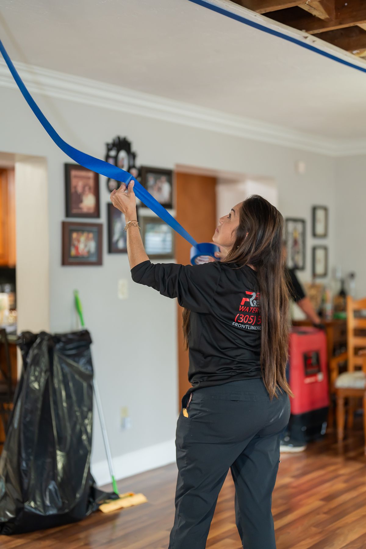 Technician sealing plastic containment sheeting inside a home