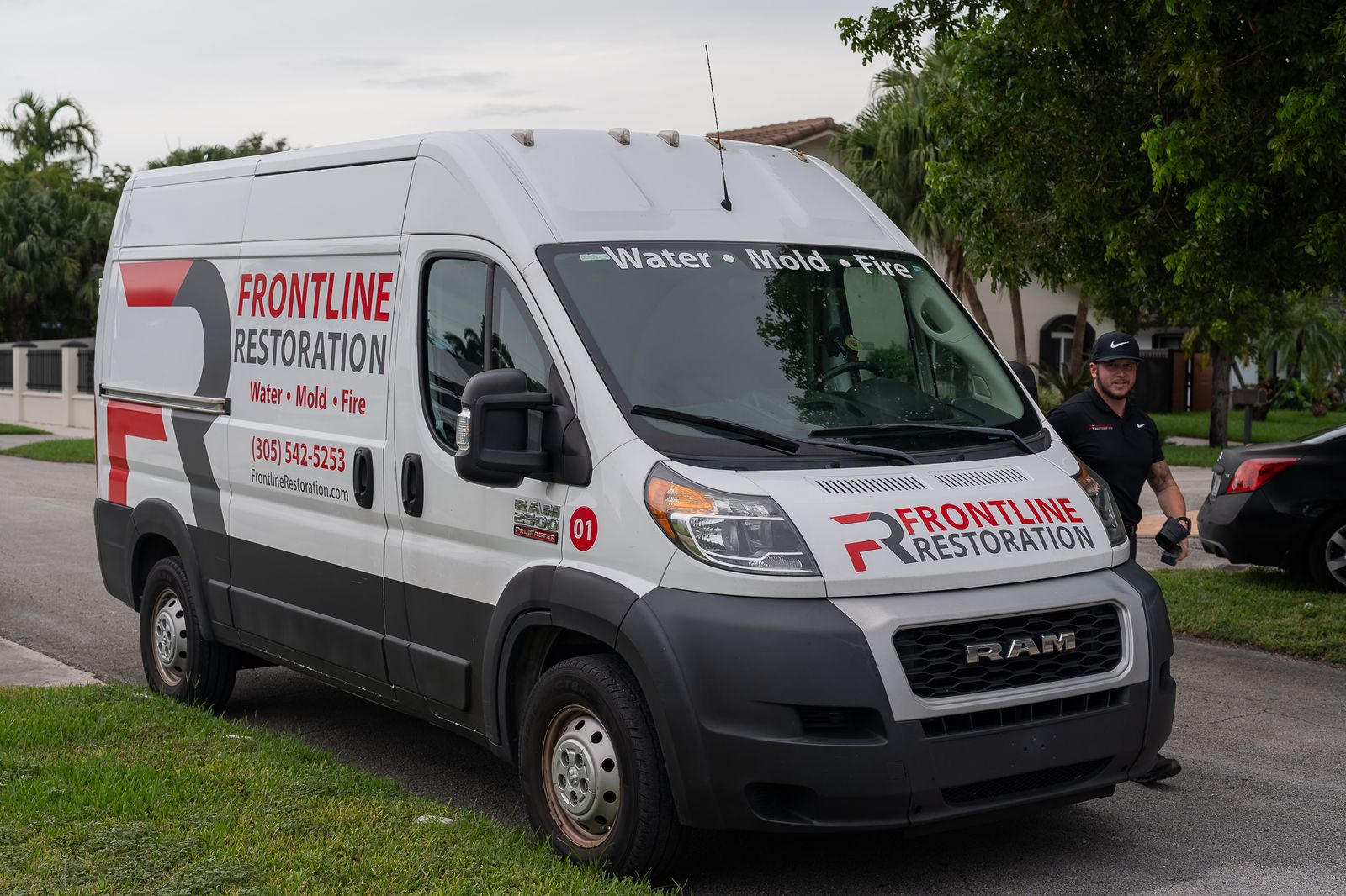 Frontline Restoration van parked in a residential driveway as a technician arrives