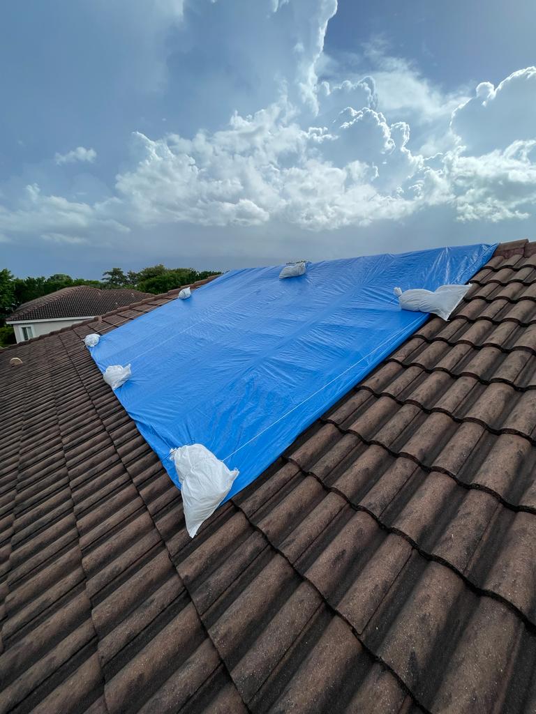 Blue tarp covering damaged roof section after South Florida storm